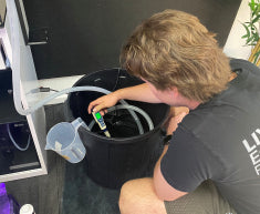 Person performing a water change on a marine aquarium using the maintenance kit
